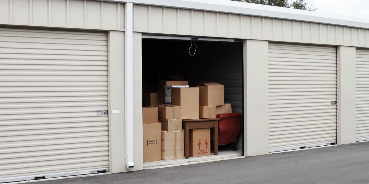 Open storage unit stacked with cardboard boxes between closed roller doors