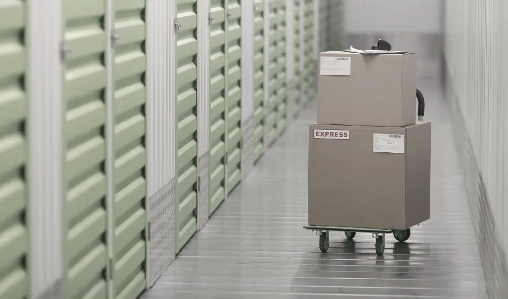 Trolley stacked with labelled cartons in a storage unit corridor